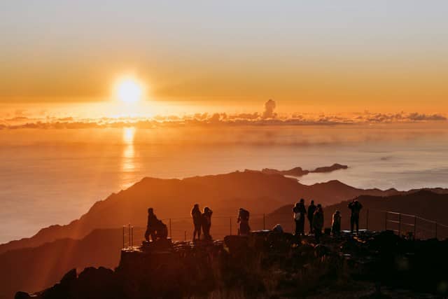 A group of people standing on top of a mountain, Pico do Arieiro, Portugal.one of the best places to travel in April