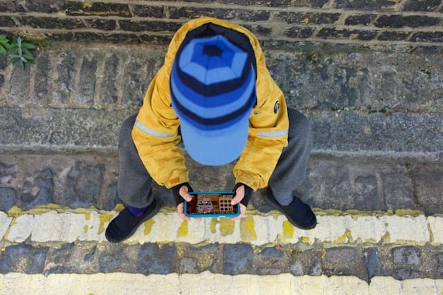 a kid kneeling on the ground looking at a cell phone