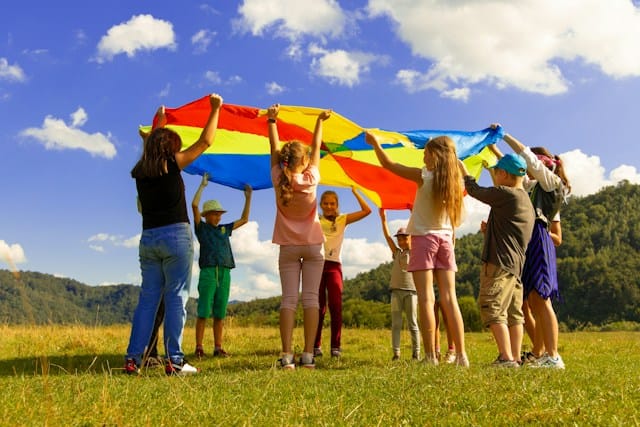 group of children standing on green grass field during daytime at summer camp