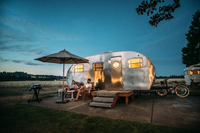 man and woman sitting in front of rv trailer at summer camp